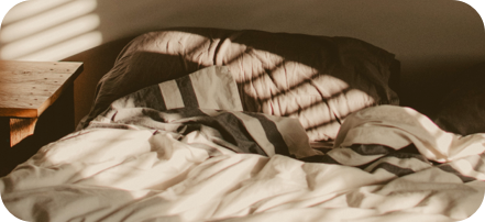 An empty bed decorated by light streaming in from a window.